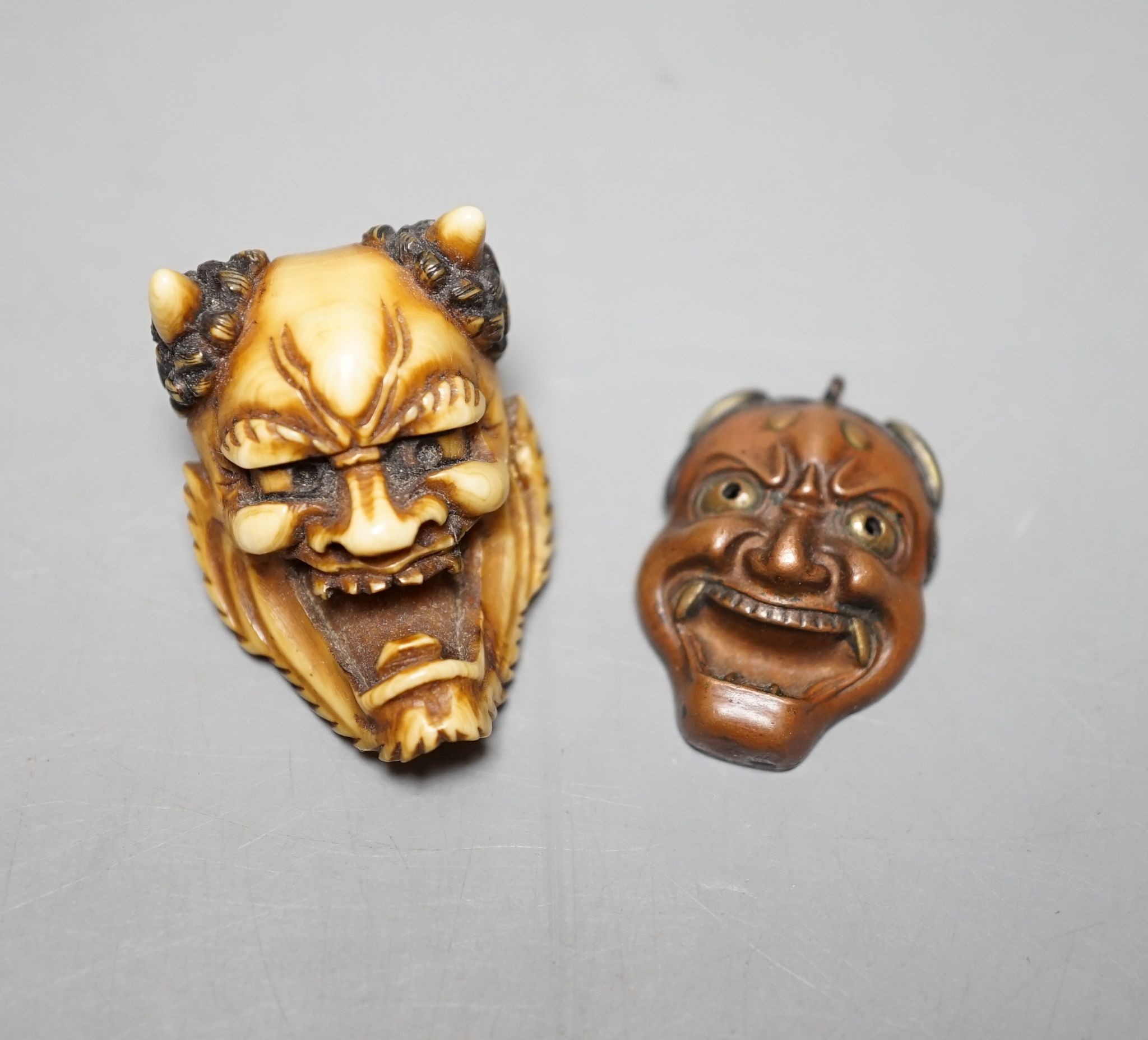 An unusual Japanese mixed metal noh mask containing minute bone dice and a stag antler noh mask brooch, signed, 3.5cm